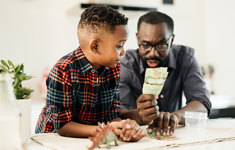 Parent holding up money while child looks on.